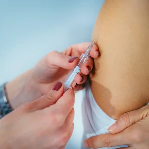 Close-up of a healthcare professional administering an injection into a patient’s upper arm, highlighting proper technique for vaccination or medical treatment.