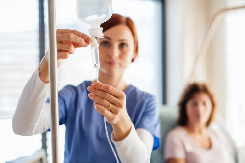 Healthcare professional adjusting intravenous drip during IV administration training with patient in clinical setting