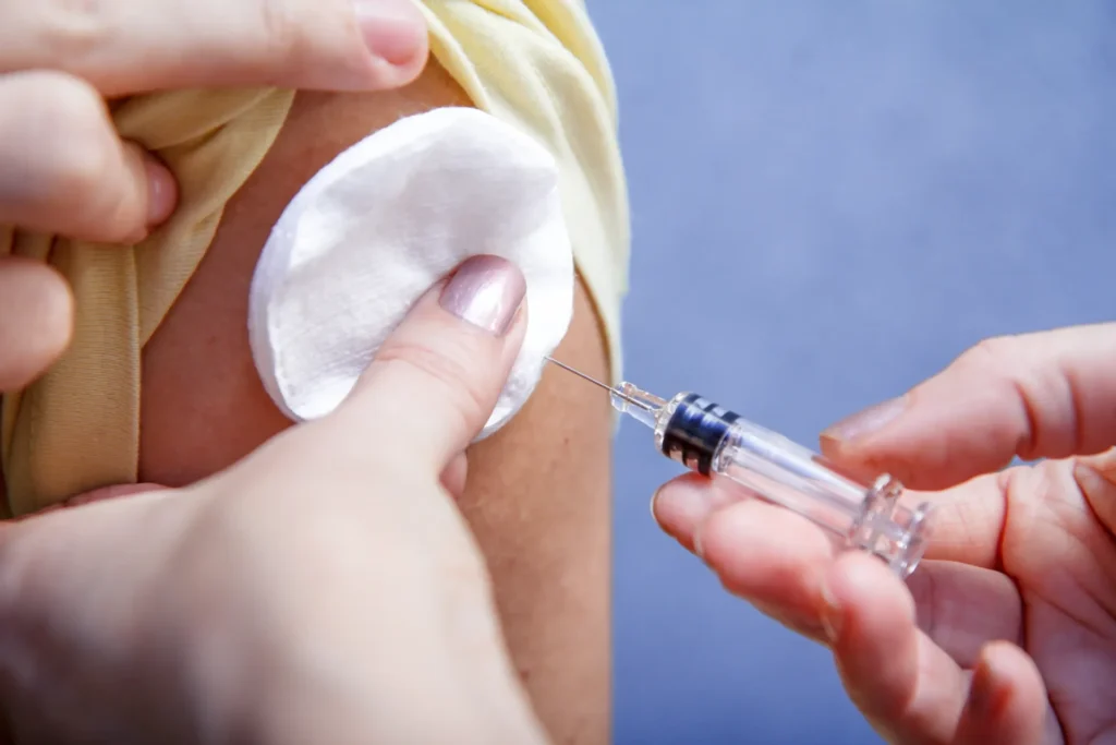 Close-up of intramuscular injection being prepared with cotton pad and syringe in clinical training environment