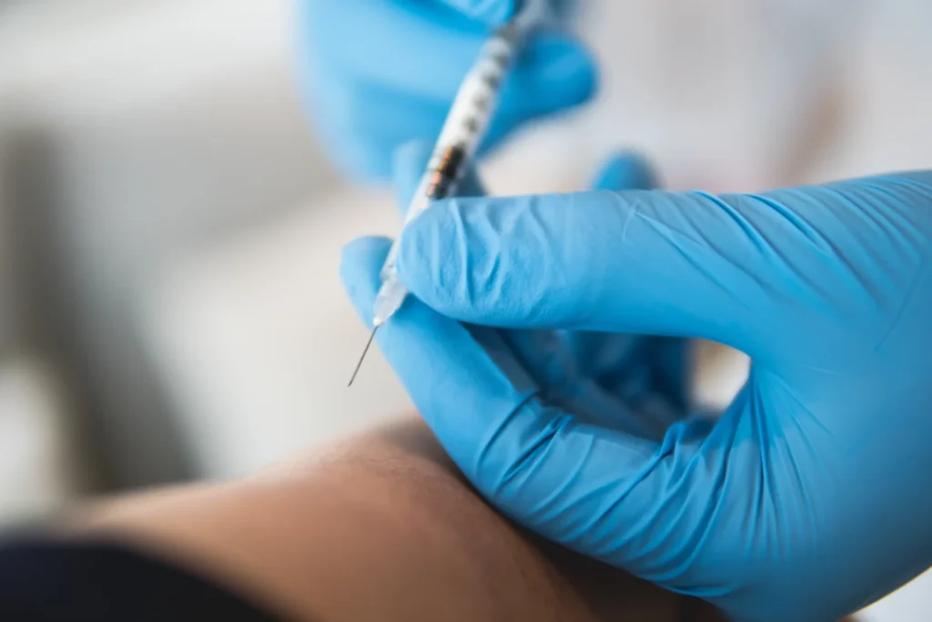 Close-up of safe intramuscular injection technique with cotton pad and syringe during injection skills training